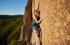 The Climber’s Guide to Pregnancy & Rock Climbing An empowered pregnant woman rock climbing safely outdoors while wearing a full-body harness, representing the journey of rock climbing and pregnancy.