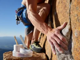 A rock climber confidently gripping a rock face with healthy hands, alongside a subtle climbing skin care kit on a nearby ledge, symbolizing preparedness and optimal hand health.