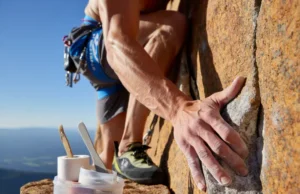 Ultimate Climbing Skin Care Kit: Your Guide to Hand Health A rock climber confidently gripping a rock face with healthy hands, alongside a subtle climbing skin care kit on a nearby ledge, symbolizing preparedness and optimal hand health.