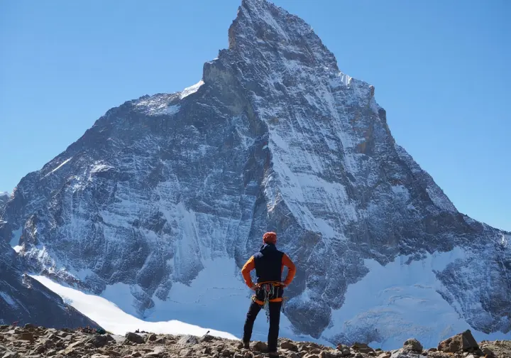 An aspiring climber stands at the base of the Matterhorn, looking up at the formidable peak in an honest appraisal of the challenge.