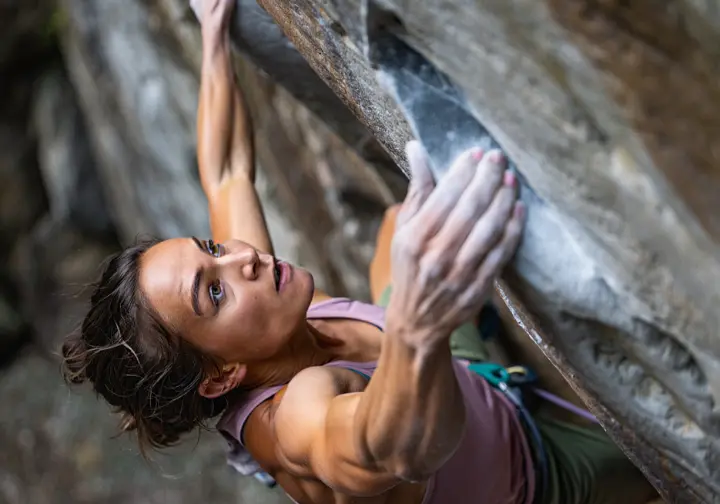 A female climber makes a powerful move on an overhang, illustrating the energy systems that power a climber's engine.