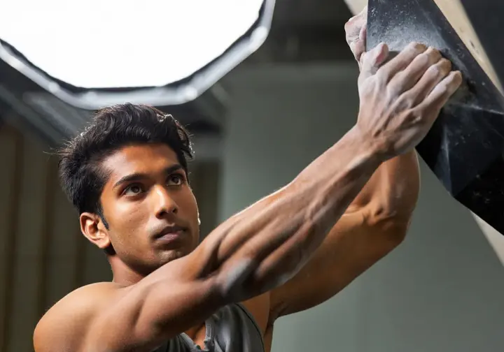 A close-up of a climber's tensed forearm and hand, showing the defined muscles that form the critical power system from forearm to fingertip.