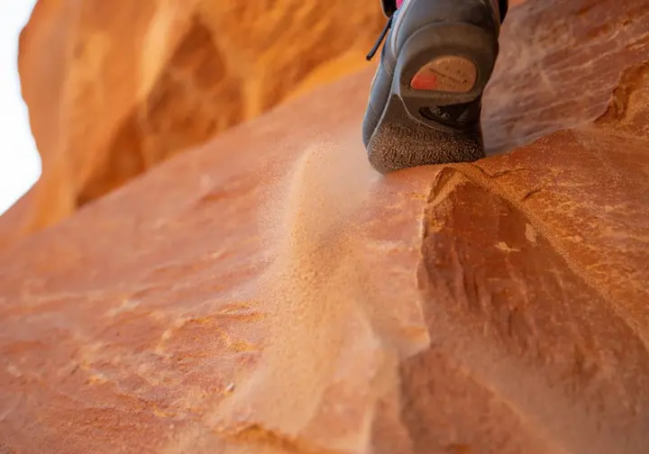 A detailed close-up of a climbing shoe's rubber sole adhering to a rock surface, illustrating the science of friction that allows climbers to stick to the wall.