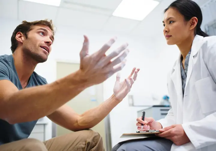 A climber trying to explain a climbing injury with hand gestures to a confused non-specialist doctor, illustrating the difficulty of communication.
