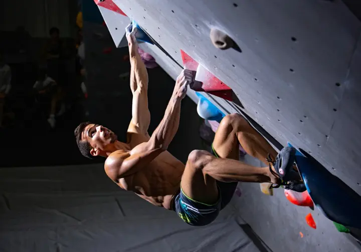 A climber uses full body tension in a drop-knee move, showing how the body's biomechanics create and control force on a steep wall.
