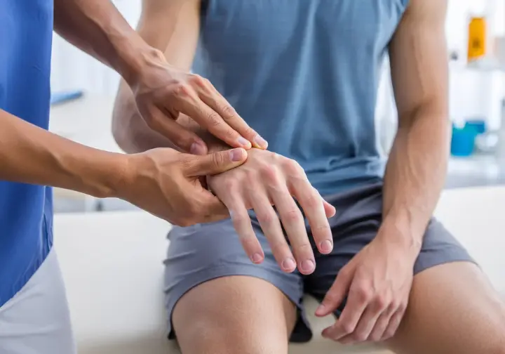 A physical therapist carefully examining a rock climber's finger to diagnose a common hand pathology like an A2 pulley sprain.