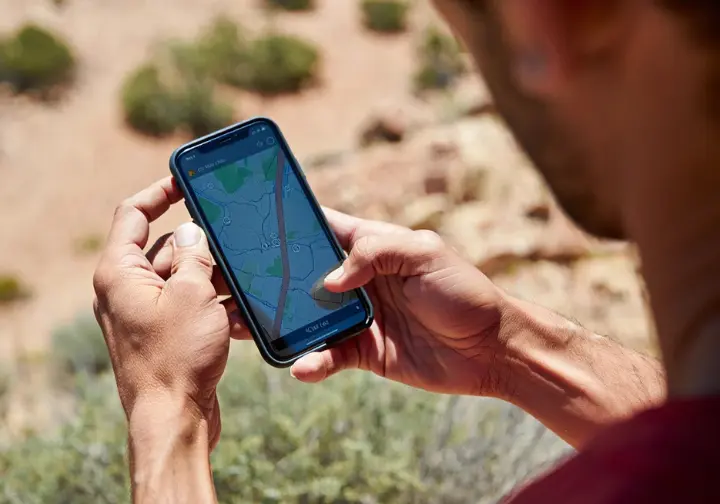 A climber in the field uses a digital mapping app on a smartphone to find free camping on public land, demonstrating a key resource from the field manual.