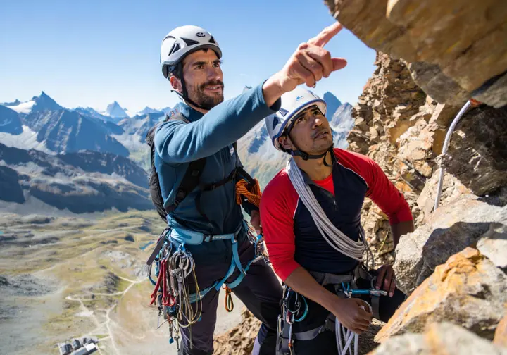 A mountain guide discusses on-mountain logistics and points out the route strategy to a climber during the ascent of the Matterhorn.