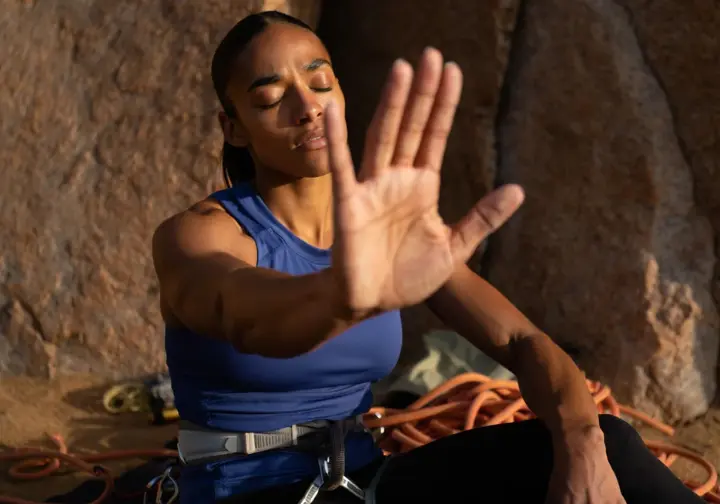 A climber sits with eyes closed, mentally visualizing a route to assess their mental strengths and weaknesses before a climb.