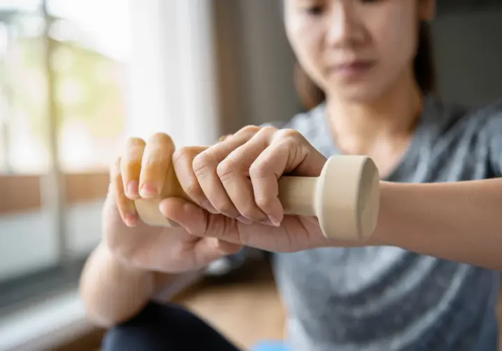 A climber on the road to recovery performs a gentle, phased rehabilitation protocol exercise with a light dumbbell for her wrist.