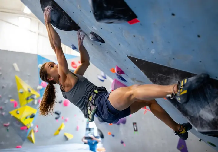 A climber demonstrates how FRC improves climbing technique by executing a perfect, deep drop-knee on a steep bouldering wall.