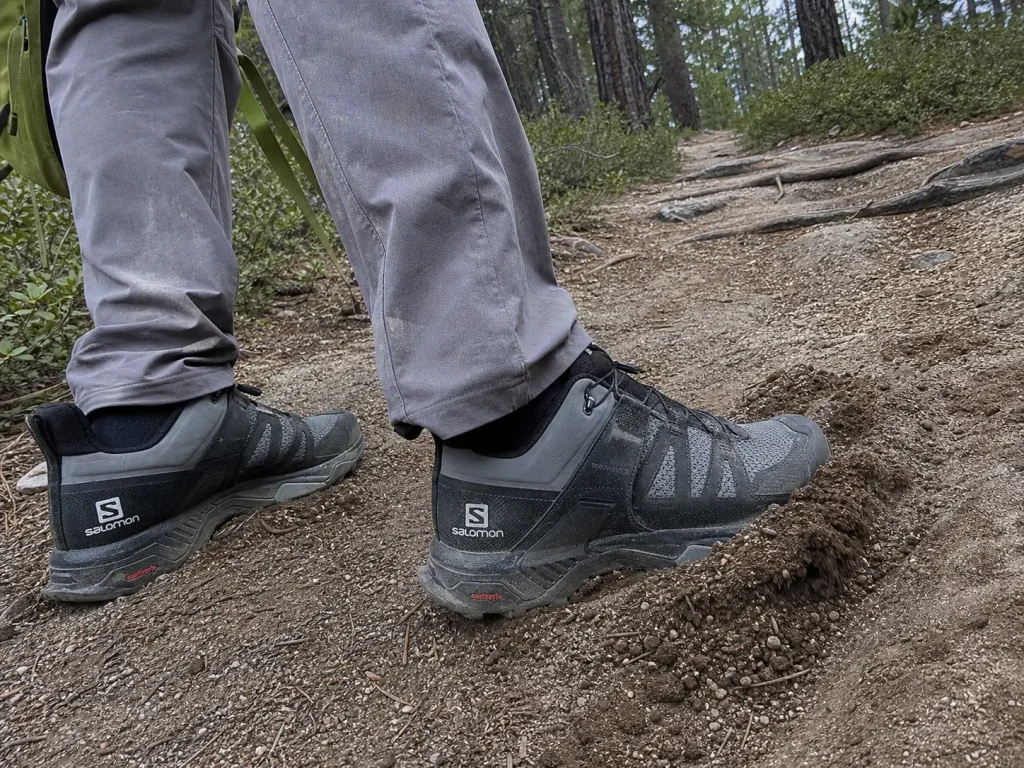 Hiking shoes with deep lugs on a loose dirt trail, built for distance not for rock