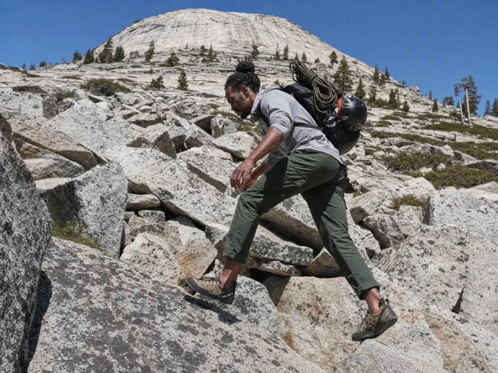 Approach shoes crossing a talus field below a granite dome, the hybrid between hiking and climbing shoes