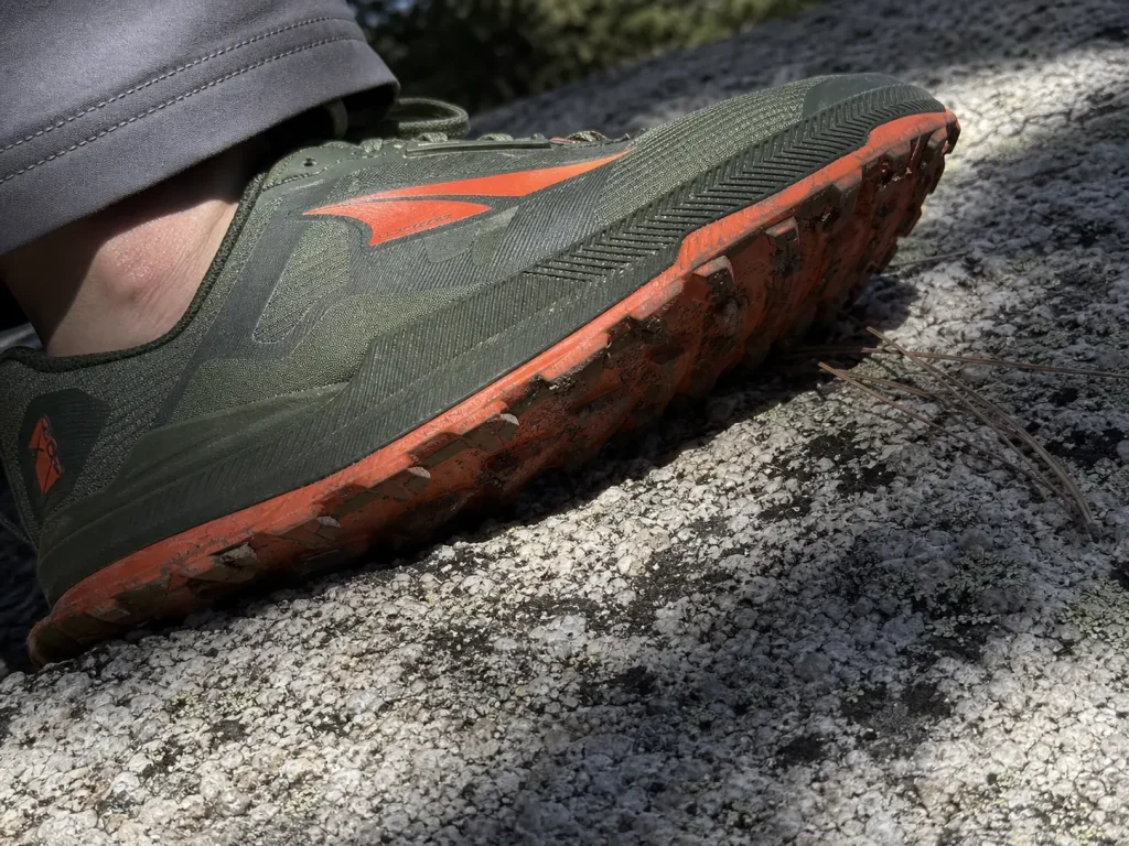 Close-up of a lugged hiking sole bridging across rough granite texture instead of gripping it