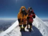 Mt Everest Expeditions 2025: Cost, Routes & Success Odds Full-body shot of two climbers in full mountaineering gear roped together, crossing a narrow snow ridge high in the Himalayas.