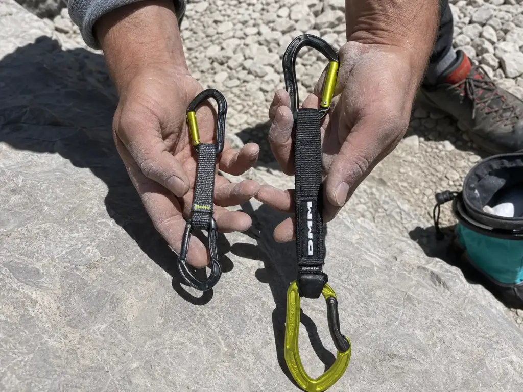Comparing short and long quickdraw dogbones side by side on a rock ledge