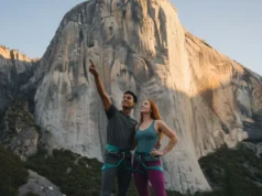 Beyond the Grade: What Historic Routes Teach Climbers Today A handsome man and a beautiful woman in athletic apparel stand at the bottom of a massive granite cliff, looking up at a historic climbing route.