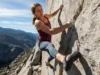 The Definitive Climbing Shoe Rubber Guide (Data-Backed) A wide, full-body shot of a fit female climber in her late 20s performing a technical move on a sunny granite rock face, with her climbing shoe precisely placed on a small hold.