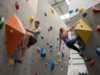The Definitive Guide: Heel Hook vs. Toe Hook Mechanics A man and woman in their late 20s demonstrating a heel hook and a toe hook side-by-side on an indoor bouldering wall.