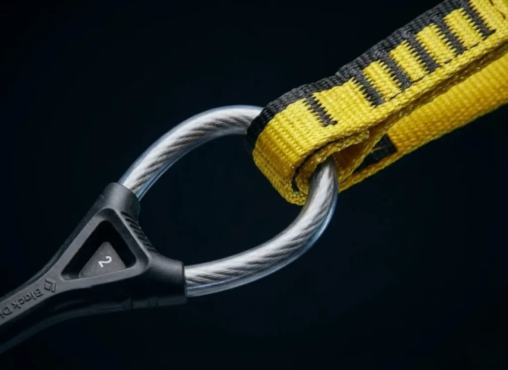 Macro close-up of a Black Diamond Camalot thumb loop cable and Dyneema sling, highlighting the tension point and material textures.