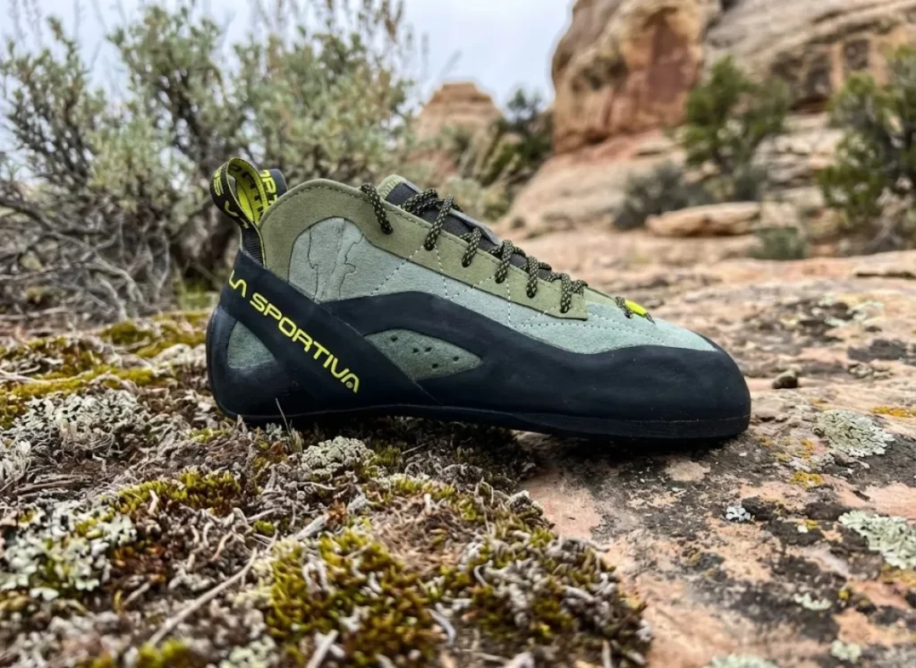 Close-up of a new La Sportiva TC Pro climbing shoe stepping on clean rock next to fragile, knobby black biological soil crust, illustrating careful foot placement.
