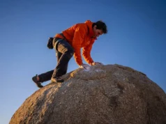 How to Mantle Climbing: The Pull-to-Push Blueprint A climber executing a difficult mantle top-out on a granite boulder at sunset, wearing Arc'teryx gear, demonstrating the transition from pulling to pushing.
