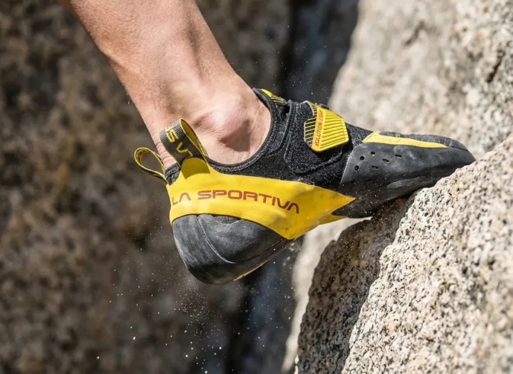 Macro shot of a La Sportiva climbing shoe executing a high heel hook on granite, demonstrating the anchor point for a technical mantle.