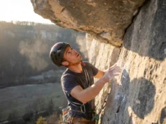 Mental Training for Climbing: A 4-Week Protocol A rock climber pausing on a steep route to mentally prepare for the next move, highlighting the psychological aspect of the sport.