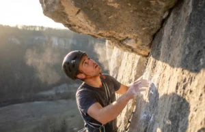 Mental Training for Climbing: A 4-Week Protocol A rock climber pausing on a steep route to mentally prepare for the next move, highlighting the psychological aspect of the sport.