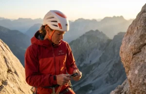 The Zero-Failure Guide on How to Rappel Safely Professional climber in Arc'teryx gear performing a safety check on a limestone cliff face during golden hour, emphasizing focus and premium safety equipment.