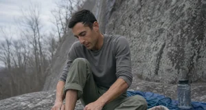 Velcro vs Lace vs Slipper Climbing Shoes by Discipline Climber lacing a La Sportiva Katana Lace shoe at the base of a gray granite crag