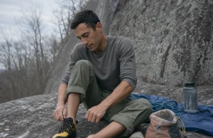 Velcro vs Lace vs Slipper Climbing Shoes by Discipline Climber lacing a La Sportiva Katana Lace shoe at the base of a gray granite crag