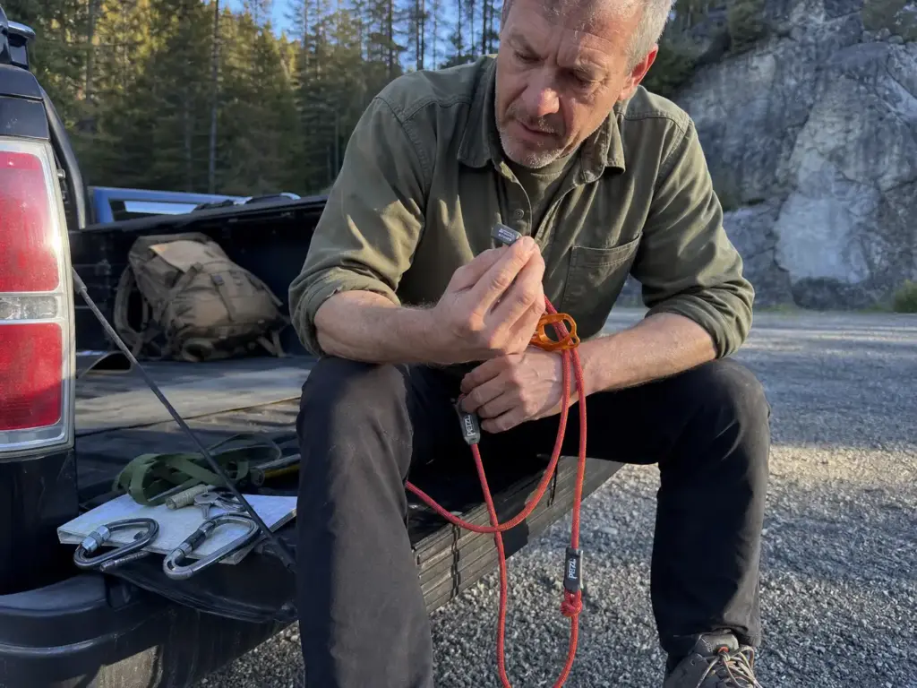 Reading the UIAA certification tag on a red dynamic belay lanyard before clipping into an anchor