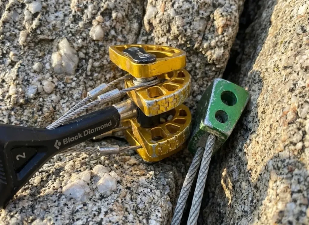 Close up of a gold Black Diamond Camalot C4 and a Metolius nut placed in a rock crack.