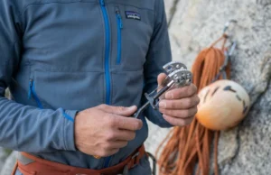 How to Clean Trad Gear: The Ultimate Stewardship Guide A climber wearing a Patagonia fleece inspects a dirty Black Diamond Camalot C4 in a workshop.