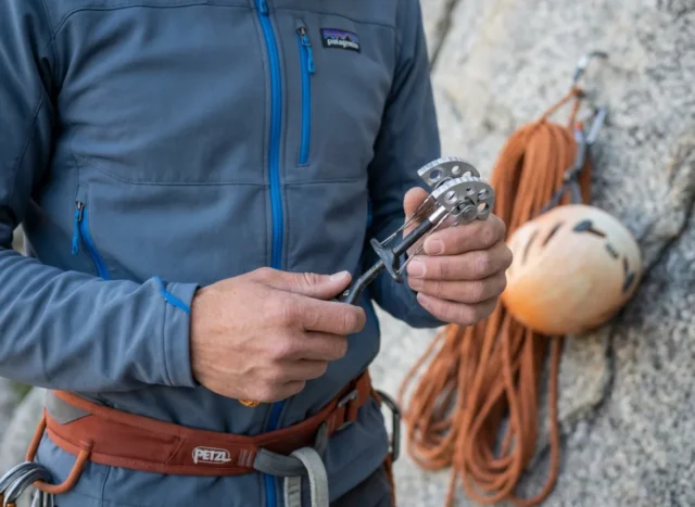 clean-trad-gear-maintenance-black-diamond-cam A climber wearing a Patagonia fleece inspects a dirty Black Diamond Camalot C4 in a workshop.