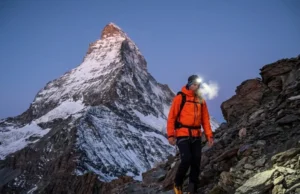 Climbing the Matterhorn: 2026 Routes & Prep Guide Alpinist wearing Mammut jacket and La Sportiva boots ascending the Hörnli Ridge at dawn with the Matterhorn summit towering above.