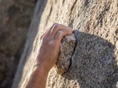 Climbing Rock Types: The Tactical Guide to Grip & Gear Close-up of a rock climber's hand gripping a rough granite edge with visible chalk and rock crystals.