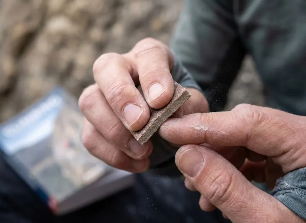 Close-up of a climber sanding down calluses on their fingertips to prevent skin injuries.