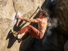 How to Dyno Climbing: Physics, Drills & Safety Climber wearing La Sportiva Solution Comp shoes and Patagonia pants executing a high dynamic move on a granite boulder.