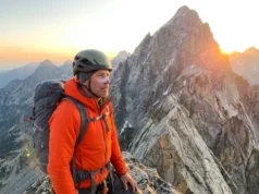 Grand Teton Climbing Guide: Routes, Gear & Training Alpinist wearing Patagonia and Black Diamond gear looking up at the Grand Teton summit during sunrise.