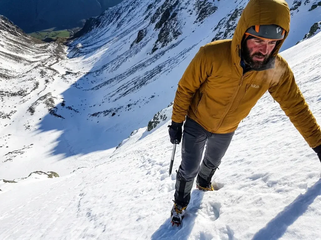 Early-season climber on snow below the Grand Teton with ice axe, season timing conditions