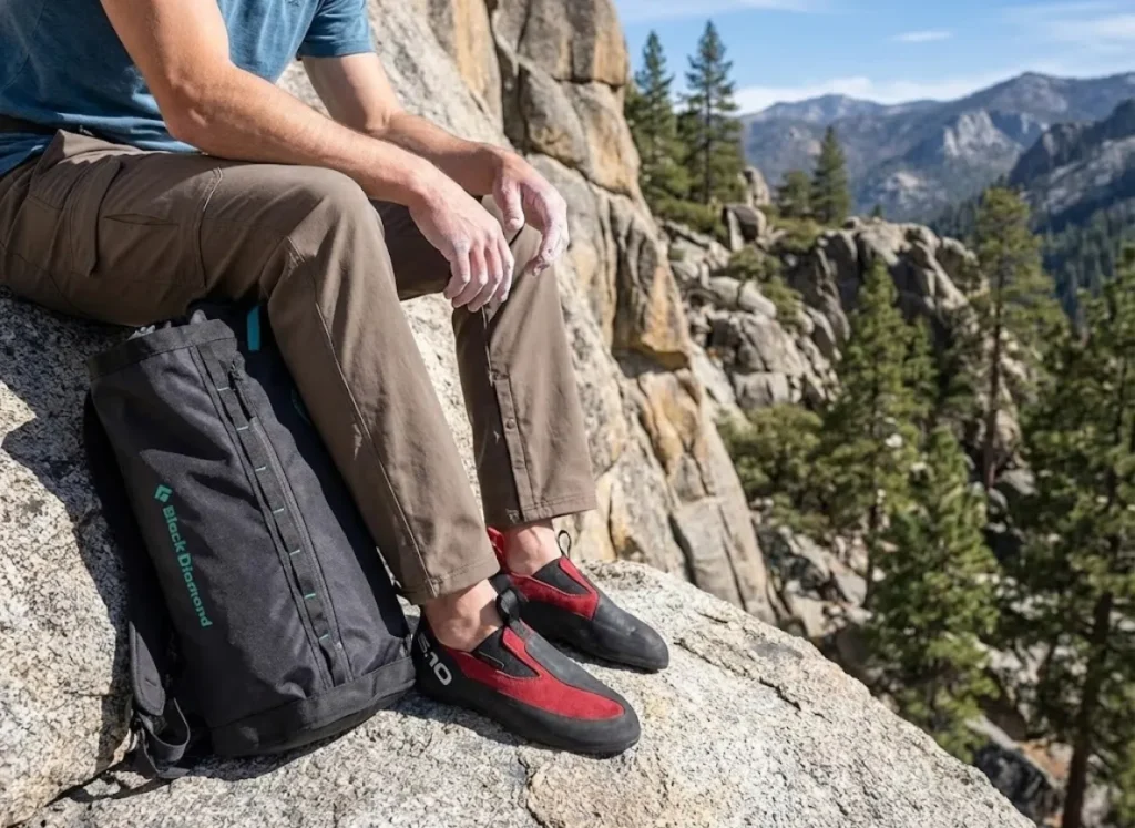 Climber in Hueco Tanks wearing Prana pants and Five Ten Moccasyms reading a guidebook amidst desert rock formations.
