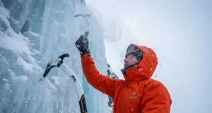 Ice Climbing Grades Explained: Angles, Gear & Conditions Climber on vertical ice wearing Arc'teryx Alpha SV jacket and using Petzl Nomic ice tools.