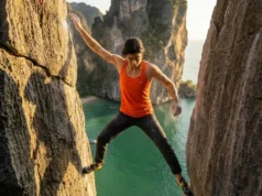Rock Climbing in Thailand: The 2026 Master Guide Climber wearing La Sportiva shoes and Arc'teryx gear stemming on a limestone cliff above the ocean in Krabi.