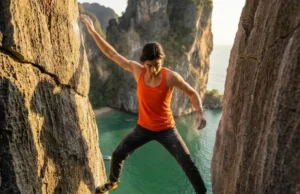 Rock Climbing in Thailand: The 2026 Master Guide Climber wearing La Sportiva shoes and Arc'teryx gear stemming on a limestone cliff above the ocean in Krabi.