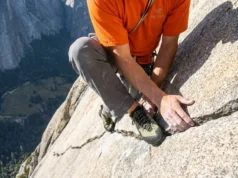 Why Chalk Fails on Granite: Friction Science by Rock Type A professional climber delicately smearing on a polished Yosemite granite slab, wearing Arc'teryx gear, highlighting the texture of the non-porous rock.
