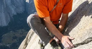 Why Chalk Fails on Granite: Friction Science by Rock Type A professional climber delicately smearing on a polished Yosemite granite slab, wearing Arc'teryx gear, highlighting the texture of the non-porous rock.