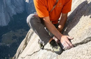 Why Chalk Fails on Granite: Friction Science by Rock Type A professional climber delicately smearing on a polished Yosemite granite slab, wearing Arc'teryx gear, highlighting the texture of the non-porous rock.