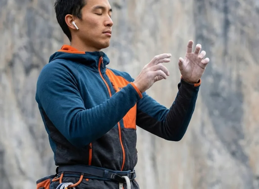 A climber visualizing a route with eyes closed, practicing moves in the air.